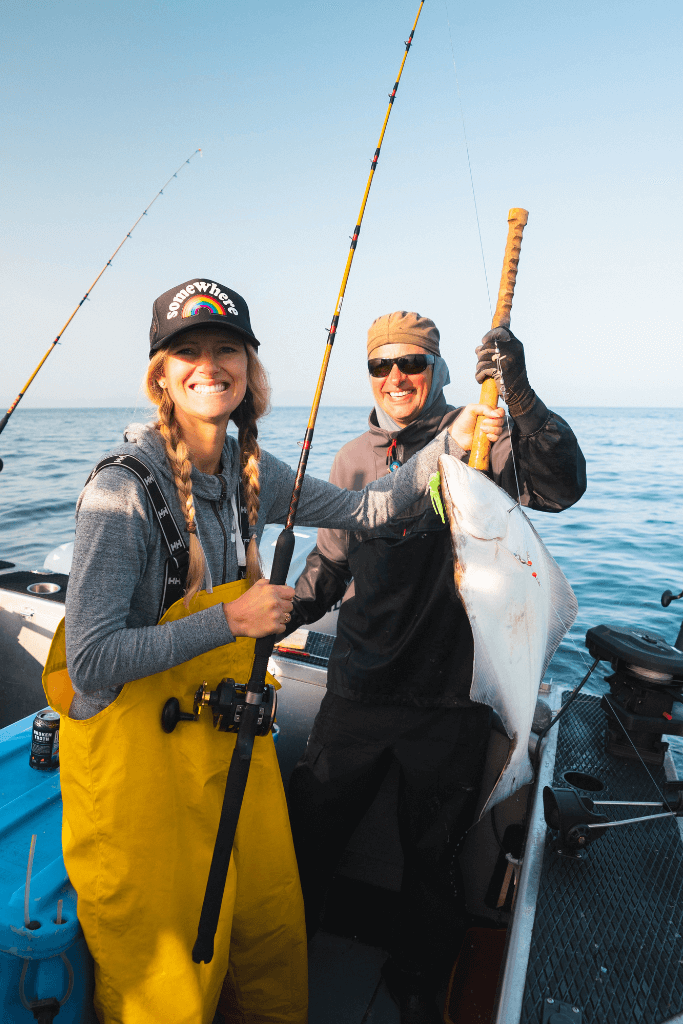 woman and man fishing, holding halibut